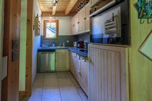 Una cucina compatta con mobili in legno, una lavastoviglie in acciaio inossidabile e una finestra che permette l'illuminazione naturale.