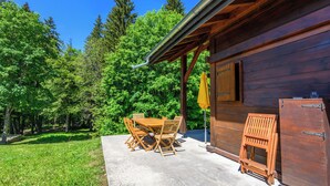 Une cabane en bois avec un patio en béton, une table à manger avec des chaises et un parasol jaune.