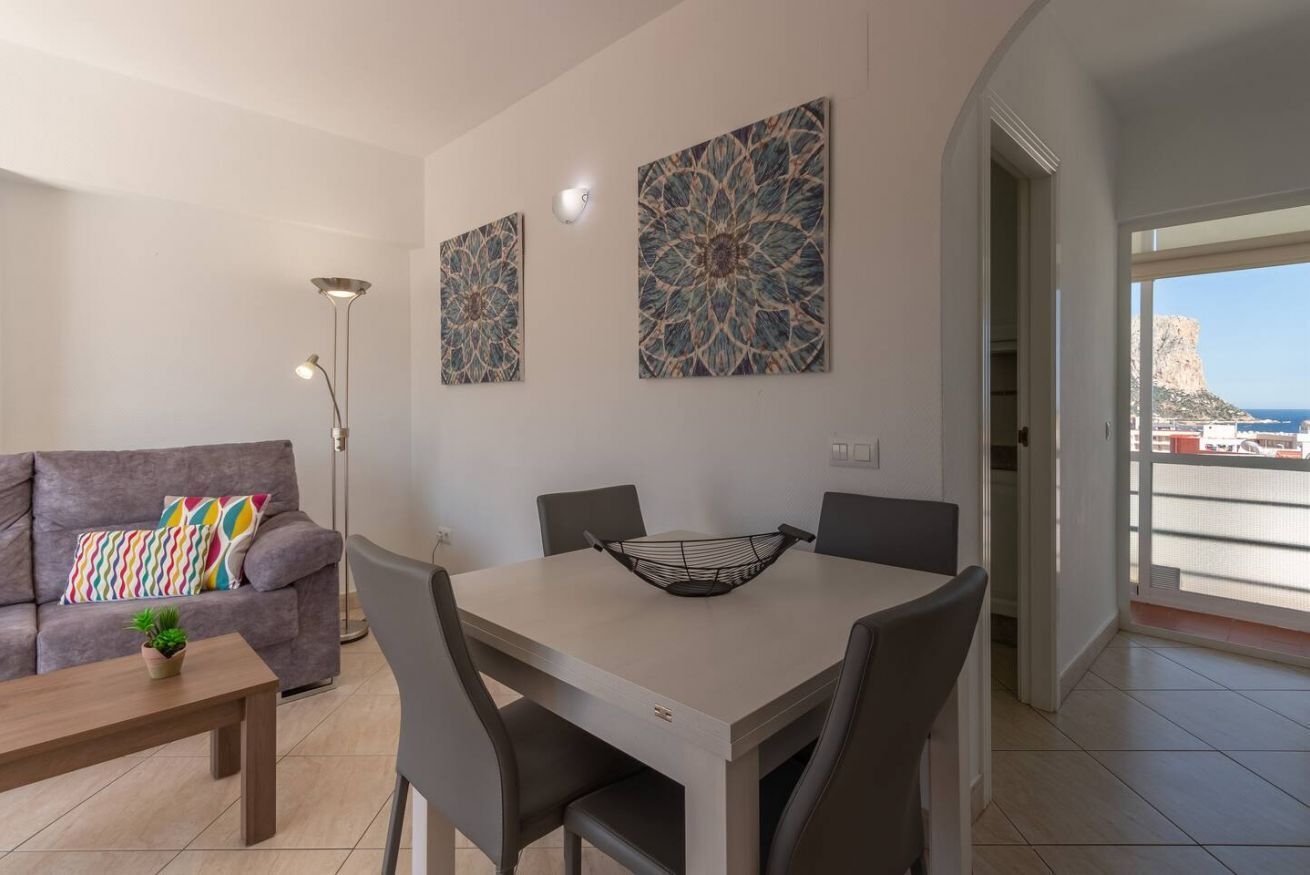 Un salon moderne avec un canapé gris, une table à manger avec des chaises et deux grandes œuvres d’art murales.