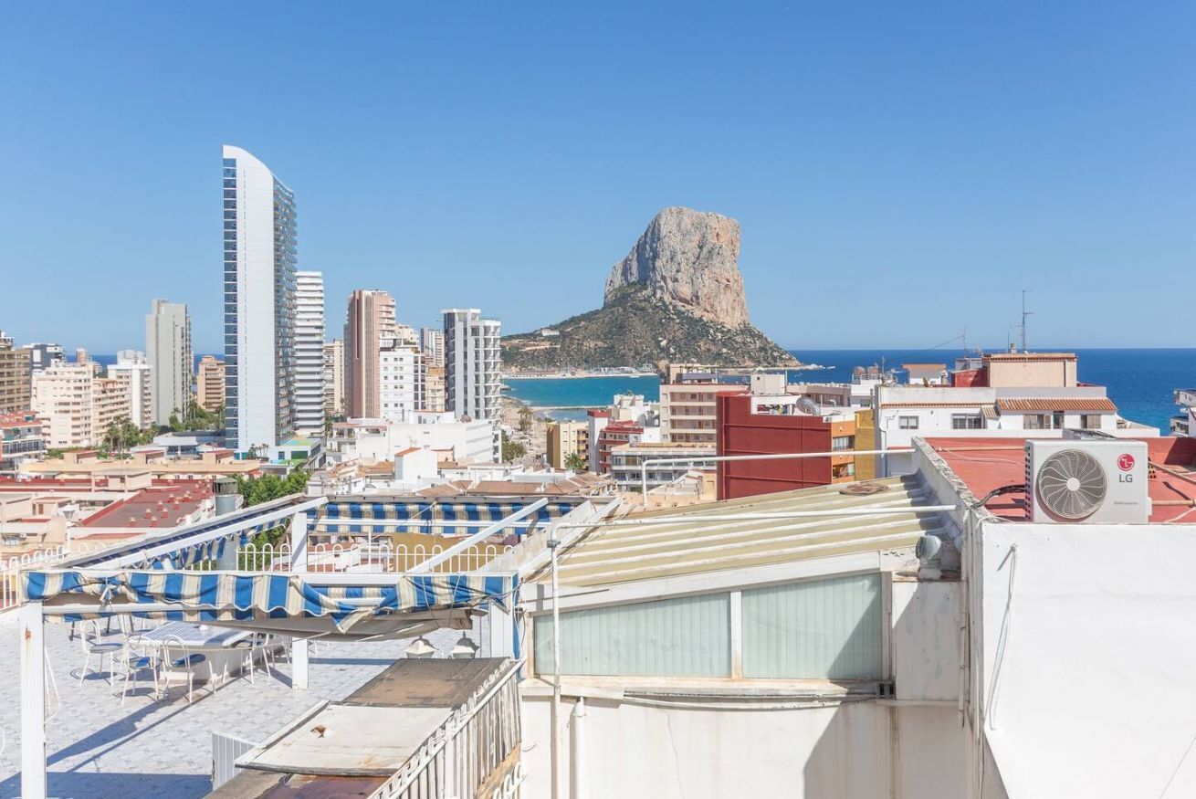 Terraço no telhado com área de estar ao ar livre e vista para a cidade e a costa.