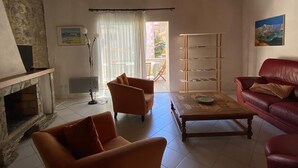 Un soggiorno con camino, un divano rosso, un tavolino in legno e una libreria.