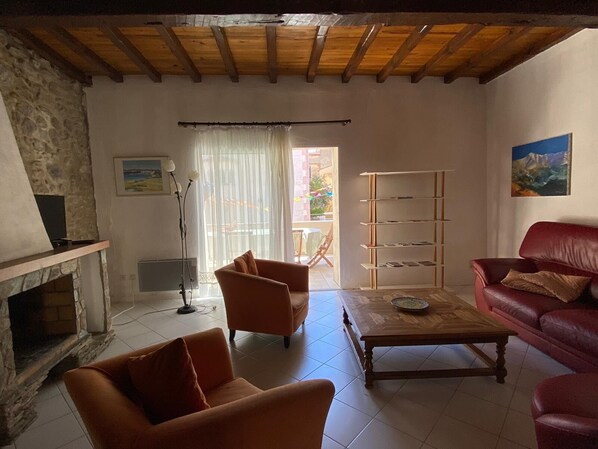 A living room with a fireplace, a red sofa, a wooden coffee table, and a bookshelf.