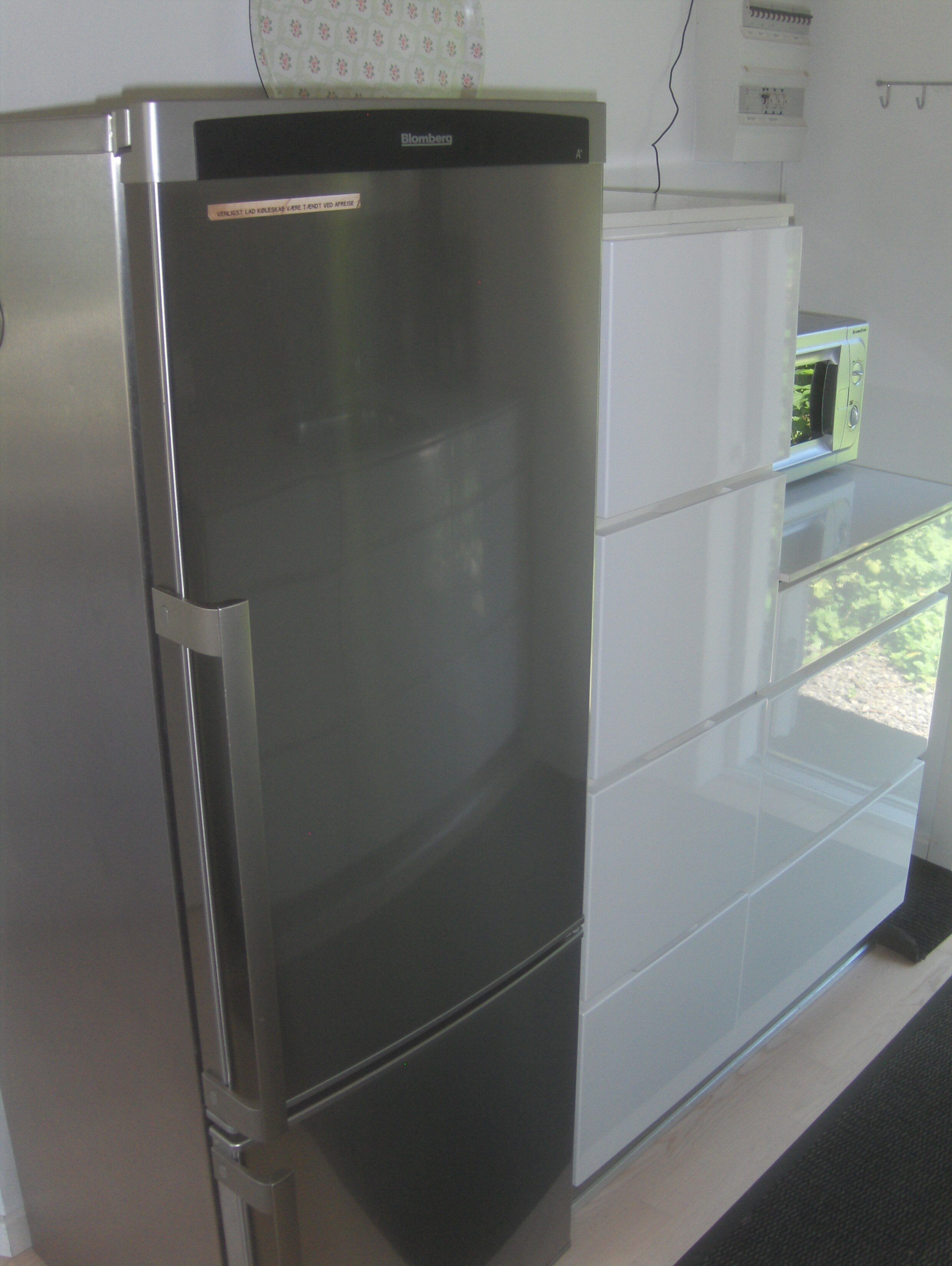 A modern kitchen with a stainless steel refrigerator, a built-in oven, and a microwave.