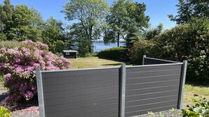 Un jardin avec une clôture en bois, un chemin de gravier et une vue sur un lac.