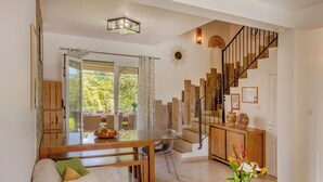 A spacious living area with a wooden staircase, a dining table, and a sofa. - 2 villas with swimming pool in an olive grove in Corsica - near Saint-Florent (Oletta)