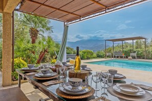 An outdoor dining area with a table set for a meal, overlooking a pool and a mountainous landscape. - 2 villas with swimming pool in an olive grove in Corsica - near Saint-Florent (Oletta)