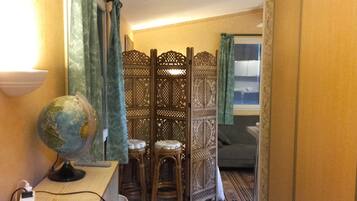 Une pièce avec un séparateur en bois, un globe terrestre posé sur un bureau et une chaise.