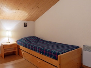 A small, single-bed room with a wooden headboard and a nightstand.