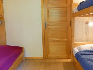 A wooden door with a handle and a keyhole, a small window, and a wooden floor. - Quiet duplex, bright living room with fireplace for 8 people (Méribel)