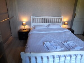 Un lit bien fait, avec du linge de lit blanc et deux lampes de chevet.
