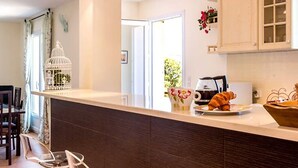 A modern kitchen with a white countertop, dark cabinetry, and a small dining area with chairs.