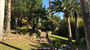 A landscaped garden with palm trees, a stone pathway, and a flower bed. - SUPER CANNES / GOLFE JUAN LUXURY APARTMENT SEA IMPRENABLE SEA. PRIVATE FLOOR (Vallauris)