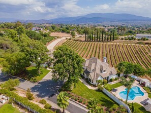 A residential area with a house surrounded by a swimming pool, a well-maintained lawn, and vineyard rows. - 7 BR/5.5 bath PERMITTED TEMECULA WINE COUNTRY VACATION RENTAL (Temecula)