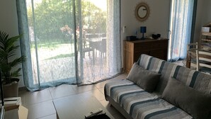 Un salon comprenant un canapé, une table basse, un téléviseur et un coin repas avec des chaises et une table.