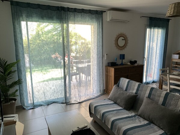 Una sala de estar con sofá, mesa de centro, televisor y un comedor con sillas y una mesa.