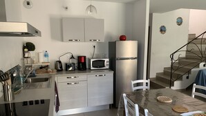 Une cuisine moderne équipée d’appareils électroménagers en acier inoxydable, une table à manger avec des chaises et un escalier menant à un autre niveau.