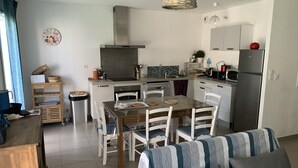 Une cuisine compacte comprenant un coin repas, une cuisinière intégrée et un réfrigérateur.