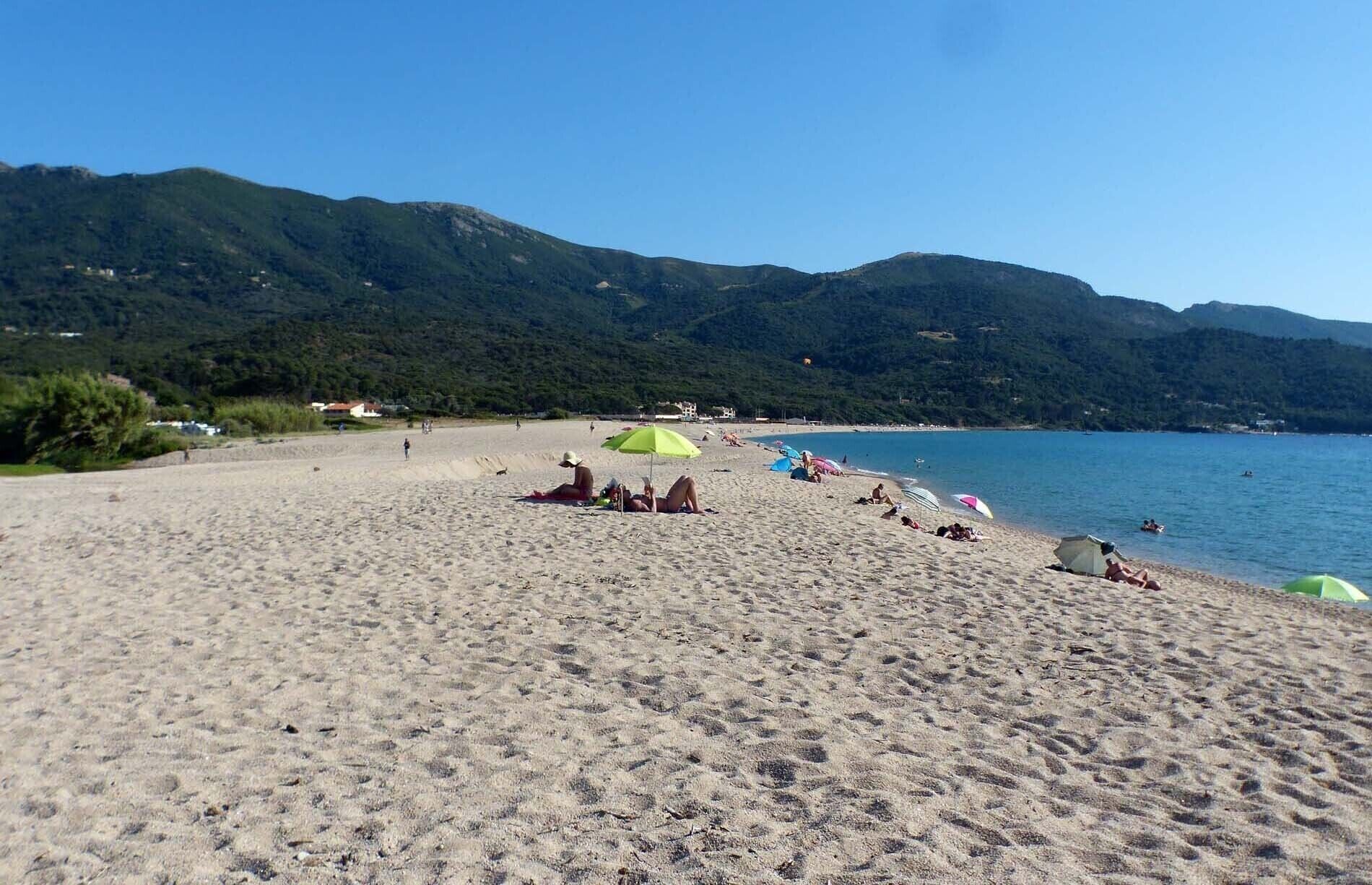 A beach with a clear view of the sea and mountains in the background.