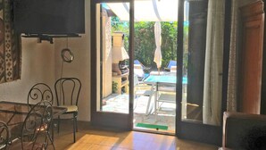 Una stanza con una porta scorrevole in vetro che dà su un’area esterna con piscina e lettini.