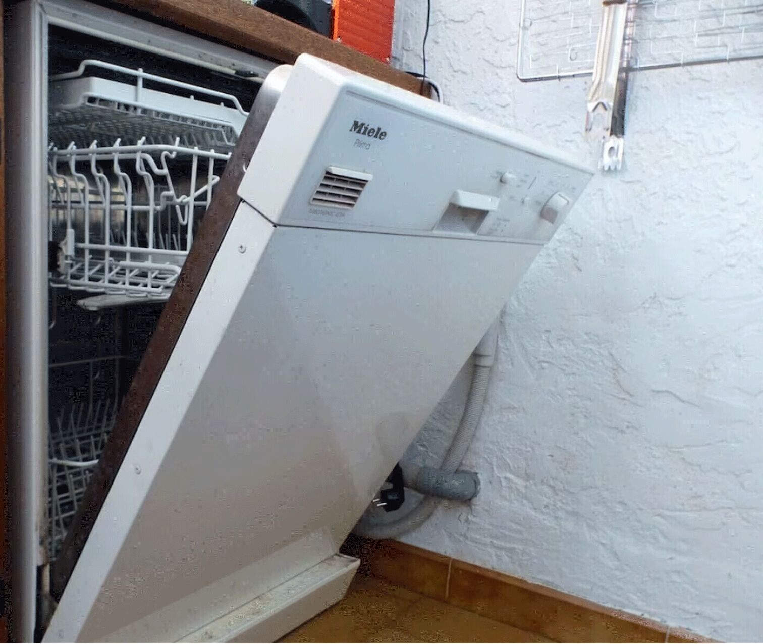 Une machine à laver Miele blanche se trouve dans une cuisine, avec un lave-vaisselle à sa gauche.