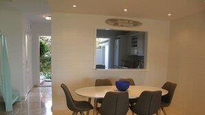 A dining area with a round table, six chairs, and a blue bowl.
