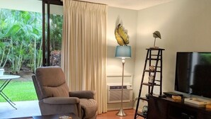 Un soggiorno con divano, tavolino, televisore e ventilatore a soffitto.