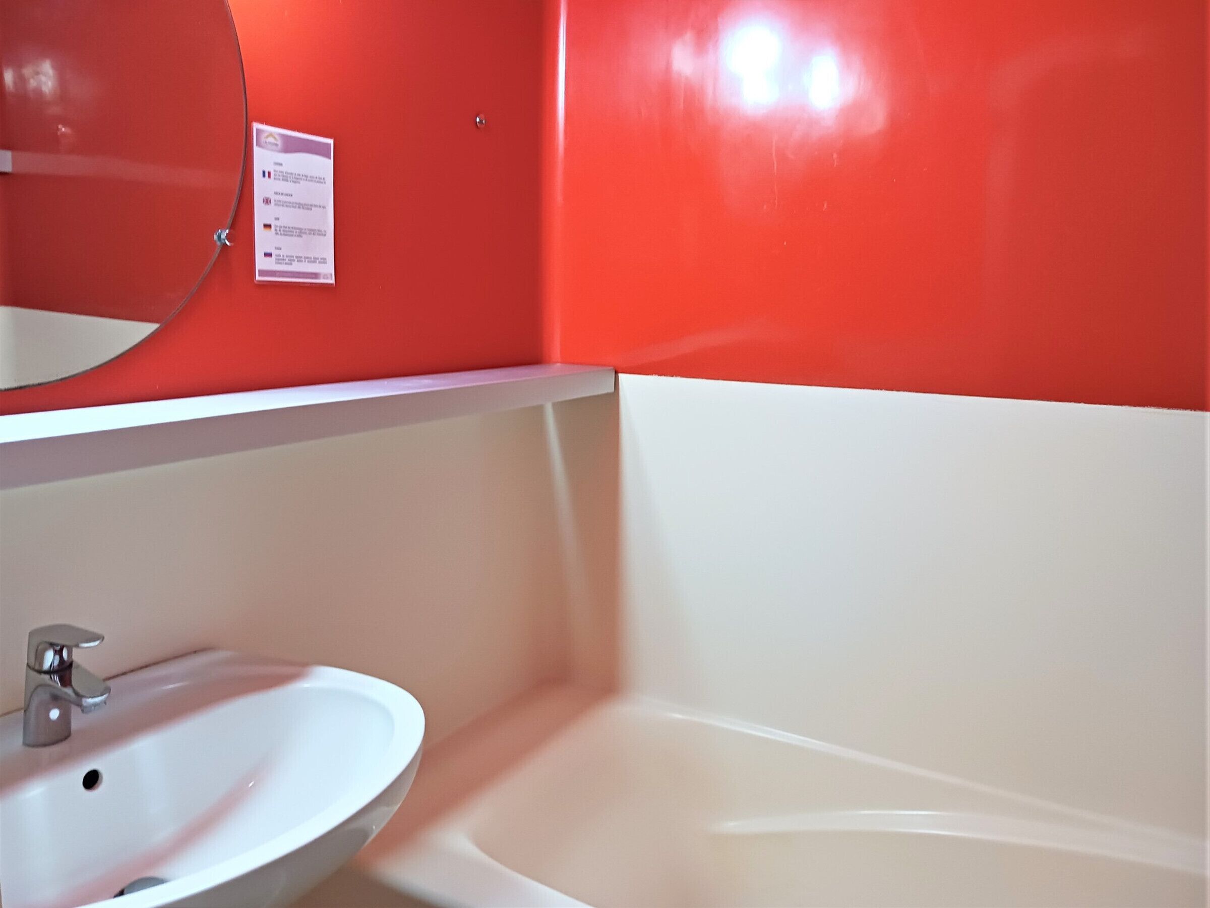 A bathroom with a white sink, a mirror, and a red wall.