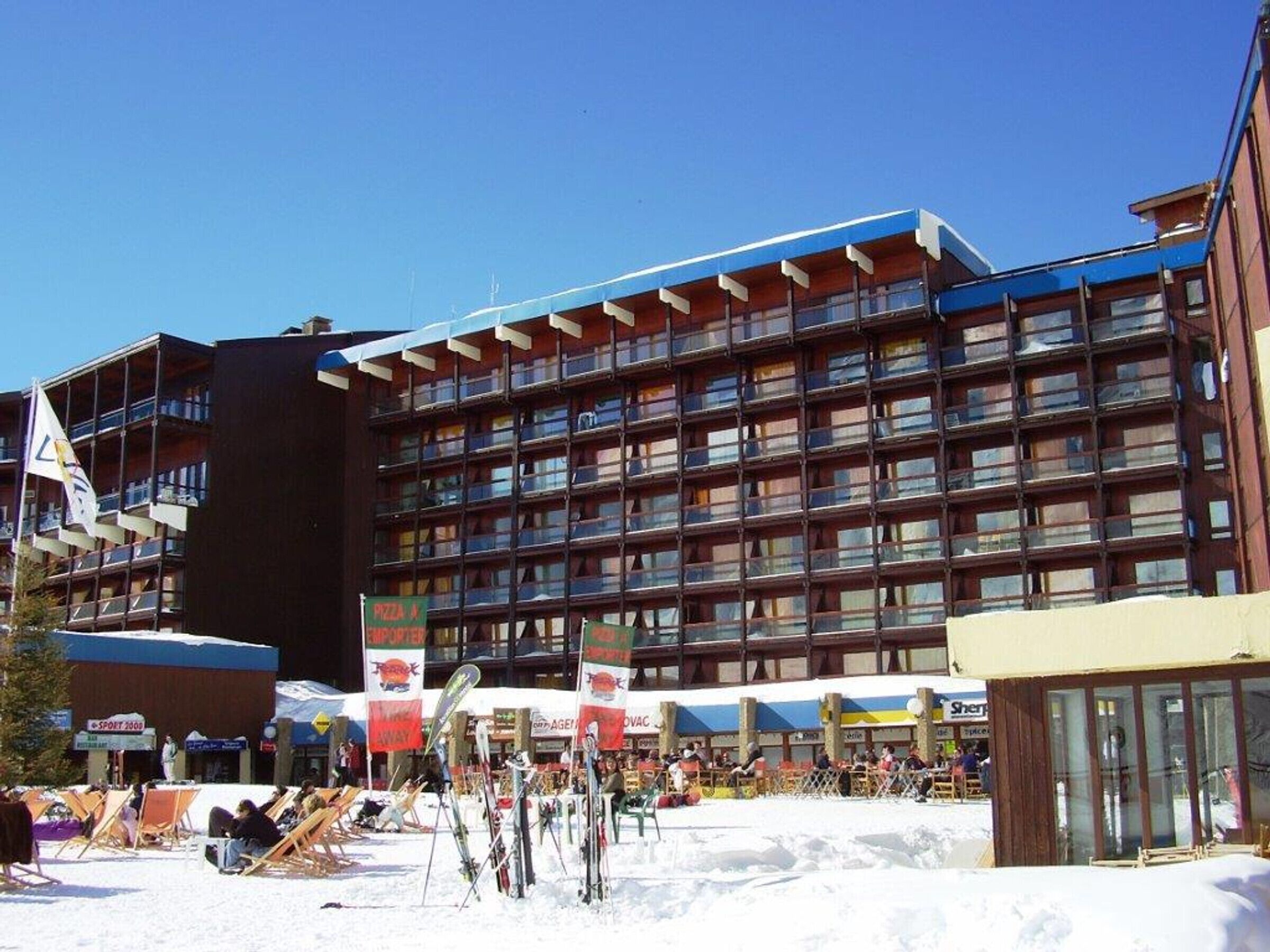 A multi-story hotel with a modern architectural design, featuring balconies and a ski resort area in the foreground.