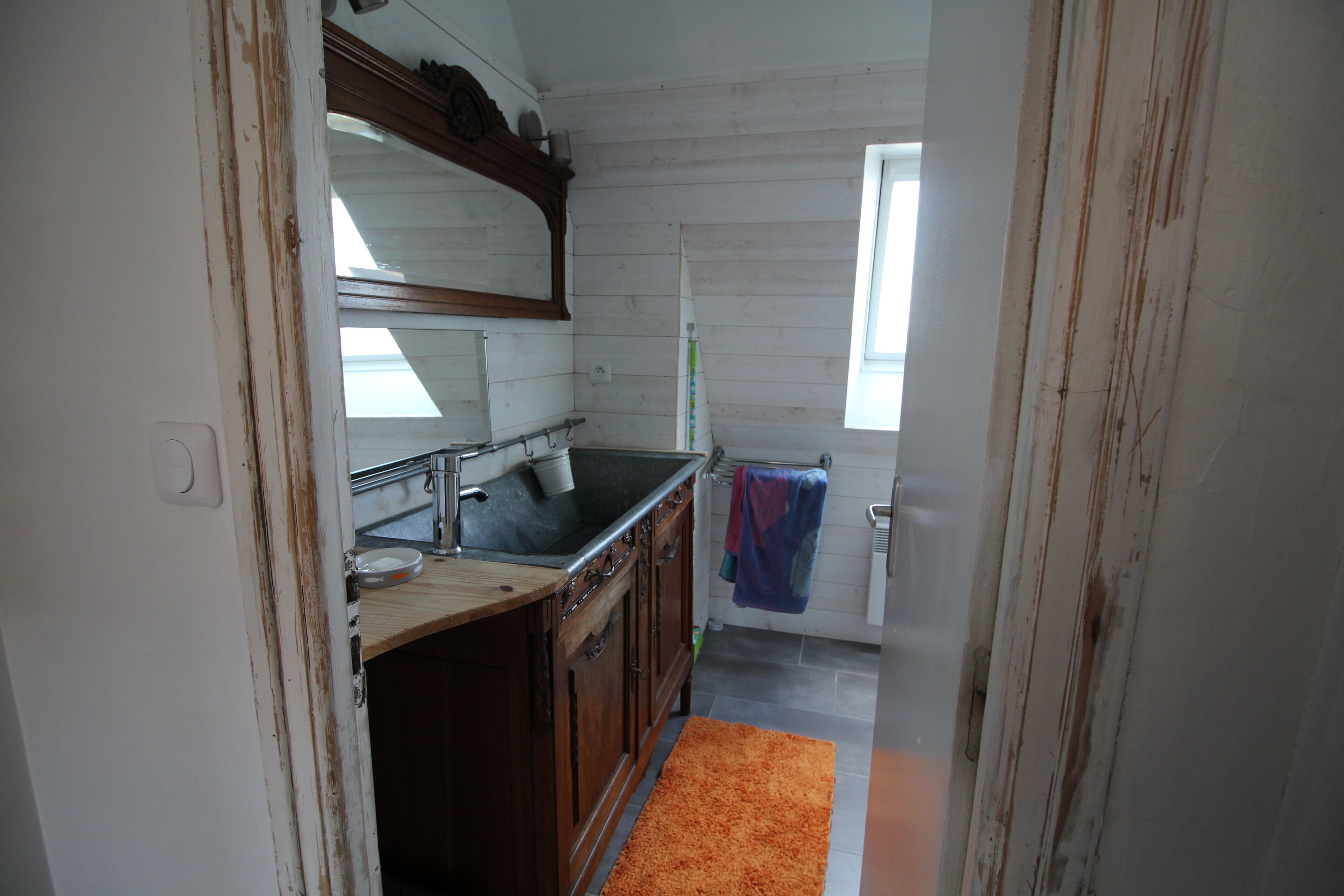 A narrow hallway leading to a bathroom with a sink and mirror.