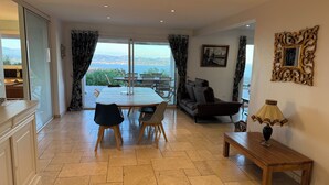 A spacious living area with a large table, sofa, and a view of the sea.