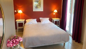 A hotel room with a large bed, two bedside tables with lamps, a framed picture on the wall, and a window with curtains.
