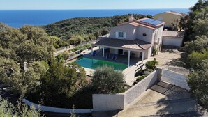 A villa with a swimming pool, a covered patio, and a view of the sea.