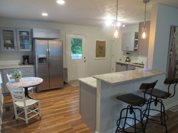 Une cuisine moderne dotée d’un îlot central, de planchers en bois et de tabourets de bar.
