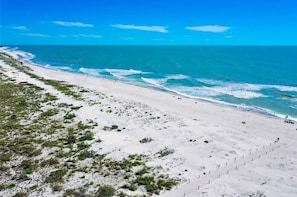 A beach with a clear view of the ocean and a sandy path leading to the water.