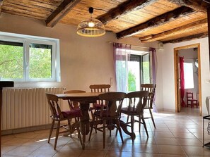 Un comedor con una mesa y sillas de madera, una lámpara colgante y vistas al exterior a través de una ventana.