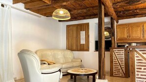 A cozy living room with a leather sofa, a round coffee table, and a wooden ceiling. - Cottage rental between Cahors and St Cirq Lapopie (Arcambal)