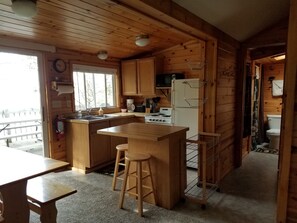 Kitchen features a central island with stools, refrigerator, stove, microwave, sink, coffee maker, and fire extinguisher.
