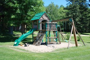 Children can play on the slide and swing set in this playground.