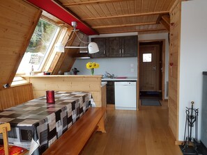 A cozy loft-style room with a wooden ceiling, a dining table with a checkered tablecloth, a red bucket, and a bench. - Chalet les Epilobes with its unusual pointed hat and breathtaking view! (Xonrupt-Longemer)