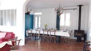 Een eetruimte met een witte tafel, stoelen en een kroonluchter.