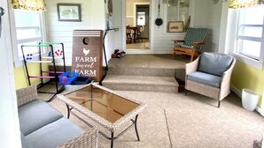Ein gemütliches Wohnzimmer mit einem Glastisch, Korbmöbeln und einem Schild mit der Aufschrift Farm sweet Farm E Johnsons.