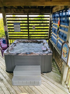 Un jacuzzi con terraza de madera, un cartel con las normas del spa y un letrero que indica 'No se admiten mascotas'.