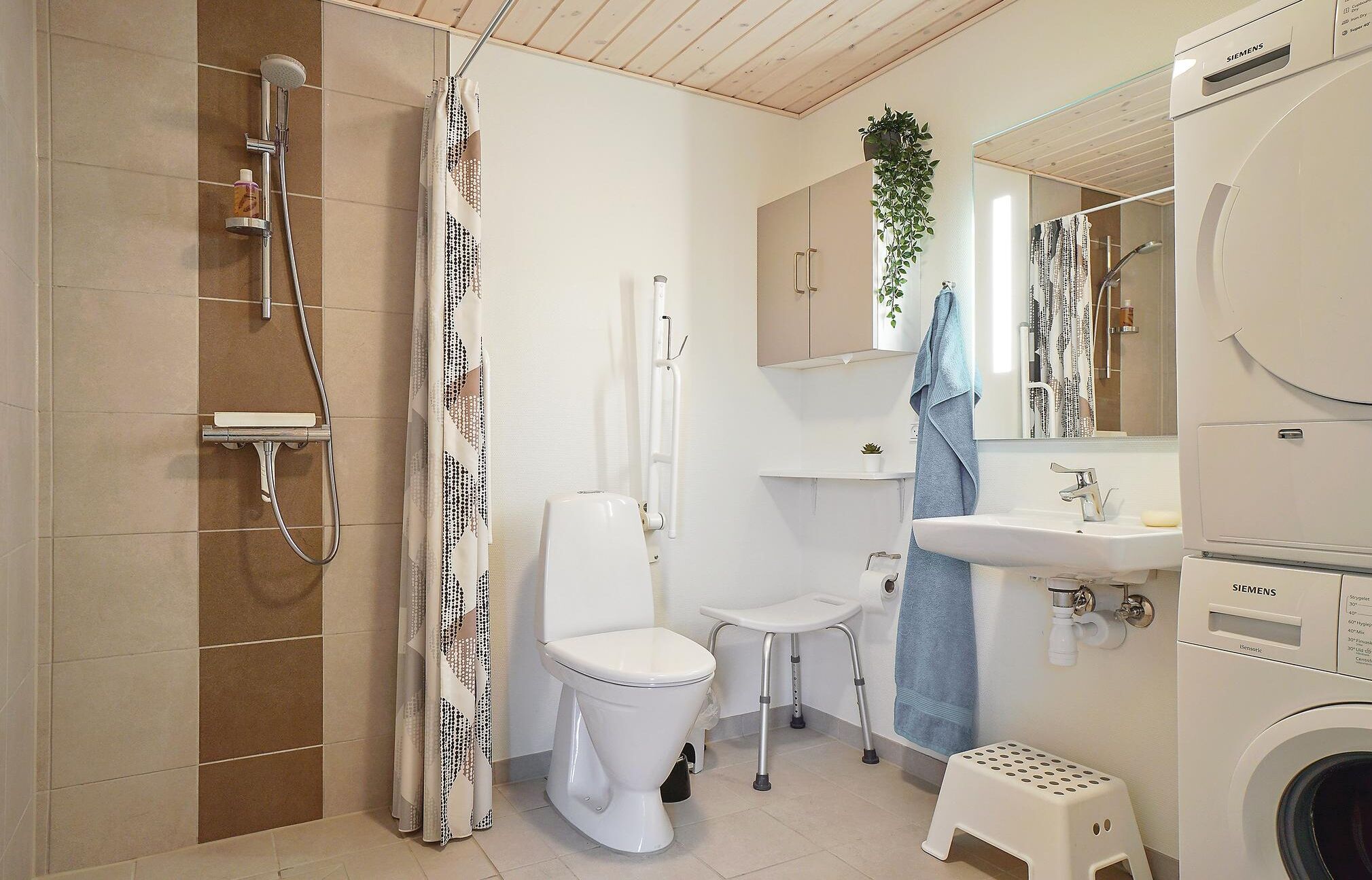 Une salle de bain moderne équipée d’une douche, de toilettes, d’un lavabo et d’un lave-linge.