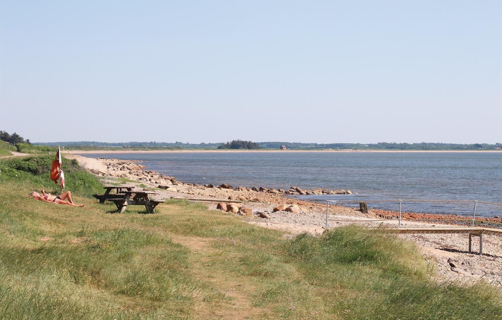 A riverside picnic area with a bench and a picnic table.