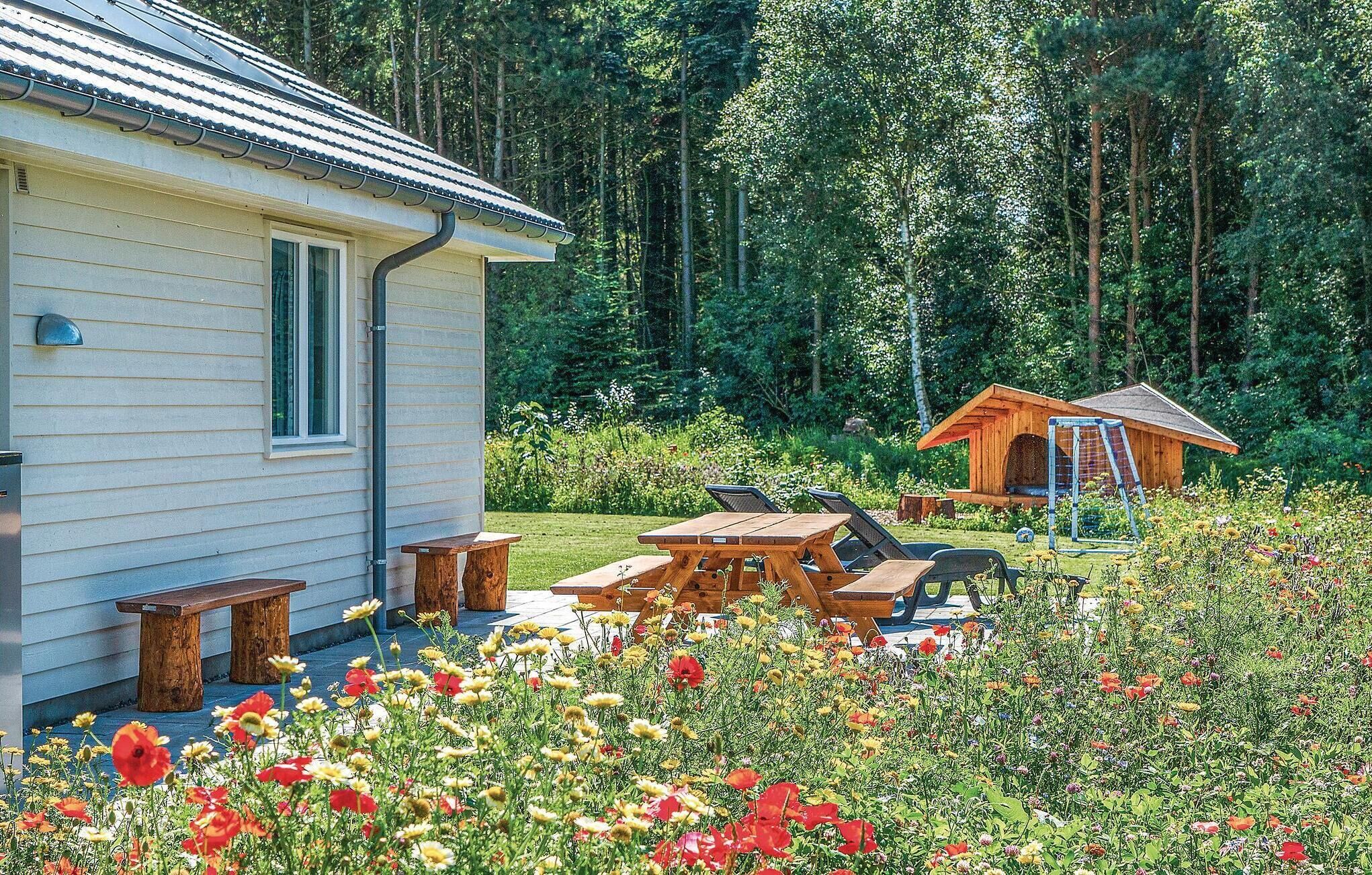 A cabin with a porch and picnic tables, surrounded by a garden with various flowers.