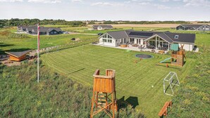 Un quartier résidentiel comprenant plusieurs maisons, une grande pelouse et une aire de jeux.