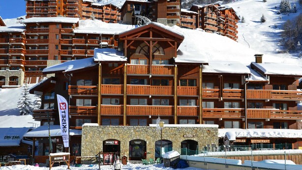 A multi-story wooden lodge with balconies, ski lifts, and a restaurant.