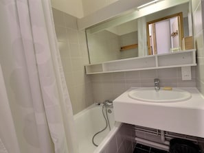 A bathroom with a bathtub, a sink, a mirror, and a shower.