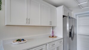 A kitchen with white cabinets, a stainless steel refrigerator, and a countertop with decorative items.