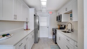 A modern kitchen with white cabinets, stainless steel appliances, and a blue rug.